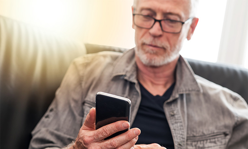 Homem idoso olhando para a tela do celular